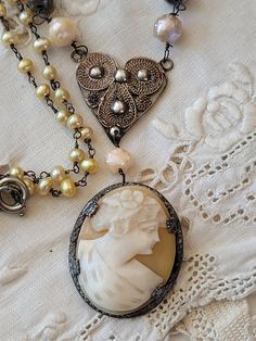 "My inspiration for this design was a beautiful antique shell cameo with a silver frame.  I left the pin on the back to not alter the antique value.  I hung her from a silver filigree heart and added a pearl chain and a couple of French bracelet pieces.    You will love her.   The length is 18 1/2\", You can hook the clasp on the pearl chain to change the length.   The cameo is 1 1/4\" long and  1 1/8\" wide." Ornate Silver Baroque Necklaces, Antique Oval Necklace For Vintage Events, Vintage Sterling Silver Jewelry For Vintage Events, Ornate Silver Necklaces For Vintage Events, Sterling Silver Vintage Jewelry For Vintage Events, Sterling Silver Vintage Jewelry For Events, Victorian Filigree Necklaces For Vintage Events, Victorian Filigree Necklace For Vintage Events, Elegant Cameo Jewelry For Vintage Events