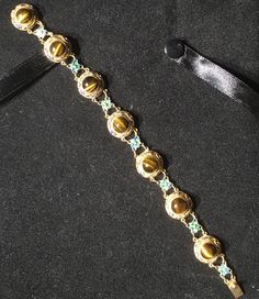 A very beautiful example of Chinese gold gilt on silver bracelet. This bracelet has bezel set round polished Tigereye stones With Enameling top and bottom and Flower links in between. Round tigereye cabochons measure 8mm with a Twist edge. There are 7 major links each set with Tigereye gold gilding all in tact . With 7 Alternate Enameled flower links . What a great gift for her absolutely near mint condition. Could become your family Heirloom . Get box with Purchase. Gold Cabochon Round Beads Jewelry, Gold Gemstone Beads And Cabochons, Gold Gemstone Round Beads, Gems And Cabochons, Luxury Gold Gemstone Cabochons, Elegant Gold Bracelets With Cabochon, Formal Cabochon Bracelet Jewelry, Elegant Gold Bracelet With Cabochon, Elegant Gold Gemstone Beads And Cabochons, Gold Jewelry With Gemstone Accents In Oval Cabochon