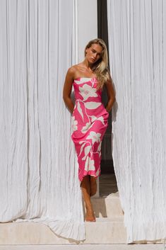 a woman in a pink and white dress standing on steps with her hands on her hips