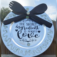 there is a plate that has some black spoons on it with the words, the secret ingredient is always love