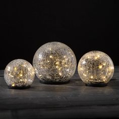 three glass orbs with lights on them sitting on a table in front of a black background