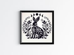 a black and white print with a rabbit in the center surrounded by flowers, leaves and moon shapes