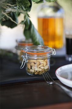 a glass jar filled with nuts sitting on top of a table next to a white plate