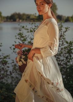 A dreamy ivory dress with floral embroidery on the net inserts, in tiers and shoulders. The tiny details in this dress are a delight. This dress is full length, buttons in front, also has a smocking detail on the waist. The romance of this dress comes to life with pink and sage flowers embroidered on the up-cycled net, the light weight cotton will make you feel like you're walking on clouds. IMPACT & CARE Made from upcycled materials Ethically made in Jaipur Hand wash in cold water FIT Your perf Cottagecore Cream Prairie Dress For Garden Party, Cottagecore Tiered Dress For Garden Party, Cottagecore Tiered Skirt Dress For Garden Party, Spring Pastoral Dress For Gatherings, Tiered Cottagecore Dress For Garden Party, Tiered Floral Embroidery Dress For Garden Party, Cream Dress With Smocked Bodice For Wedding, Cream Wedding Dress With Smocked Bodice, White Feminine Prairie Dress For Garden Party