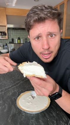 a man is holding a piece of bread in his hand and looking at the camera