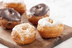 a wooden cutting board topped with donuts covered in frosting