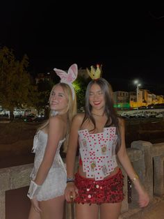 two young women dressed up in bunny ears and dresses are standing next to each other