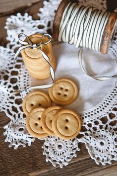 some wooden buttons are sitting on a doily next to a spool of thread