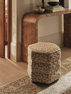 a large ottoman sitting on top of a rug next to a wooden table and door