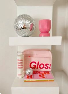 a white shelf with some pink items on it and a disco ball in the corner