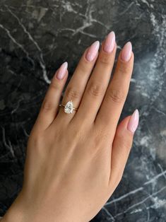 a woman's hand with pink manicured nails and a diamond ring on her finger