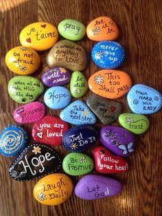 some rocks that have been painted with words on them and are in the shape of hearts