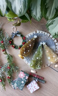 small christmas trees are sitting on a table next to wrapping paper and other holiday decorations