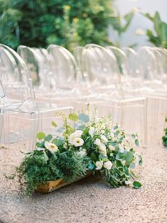 a bunch of chairs that are sitting on the ground next to each other with flowers in them