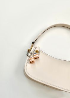 a white purse with two small pearls attached to it