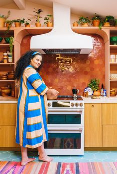 a woman standing next to an oven in a kitchen