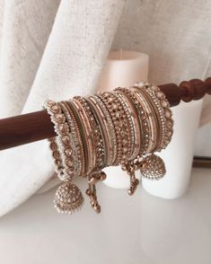 a stack of bracelets sitting on top of a table next to a white vase