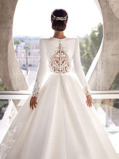 a woman in a white wedding dress standing on a balcony looking out at the city