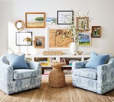 two chairs and a table in a room with pictures on the wall