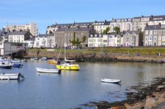 there are many boats that are in the water near some buildings on the other side of the river