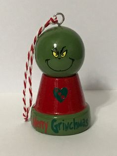 a green and red christmas bell ornament with an angry grin on it's face