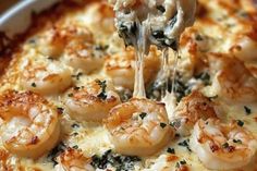 a close up of a plate of food with shrimp on it and cheese being drizzled over the top