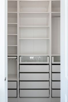 an empty white closet with drawers and shelves in the middle, filled with items for storage