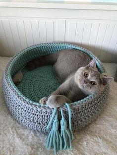 a gray cat laying in a crocheted bed on top of a white carpet