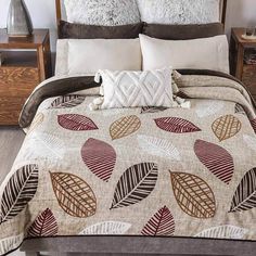 the comforter is made up and has many leaves on it, as well as two pillows