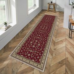 a large red rug on the floor in a room with wooden floors and white walls