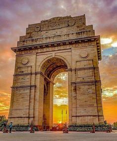 the sun is setting behind an arch in india