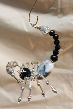 a beaded spider is hanging from a hook on a white sheet with black beads