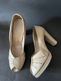 The 1970s were so good at doing the 1930s and 1940s and these shoes are a perfect example.  They are made in England by Ravel.  They are a great version of 40s peeptoe platforms.  They are made in pale beige with a darker beige trim and stitch detail.  They have a wrapover effect at the front.  They slip on.  The heel is enclosed.  The platform is 0.5 inches tall and the heel is 4 inches (10cm) tall. I am not sure if the uppers are leather or not.  The interior is not.  Nor is the platform, heel 1940s Shoes, Beige Trim, Pale Beige, Platform Shoes Heels, Pumps Shoes, Dark Beige, Platform Heel, Packing Material, Heels Shoes