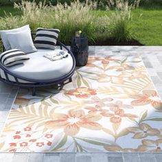 an outdoor area rug with flowers and stripes on the ground next to a lawn chair