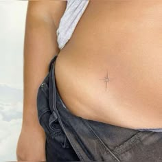 a cross tattoo on the back of a woman's stomach