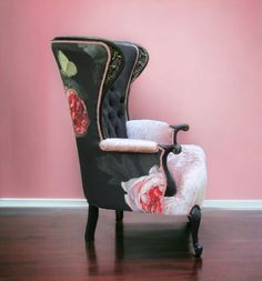 a black chair with pink roses on the back and white upholstered seat, in front of a pink wall