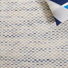 an upholstered rug with blue and white squares on the bottom, next to a pillow