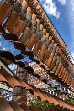 a large wooden structure with lots of pots hanging from it's sides and the sky in the background