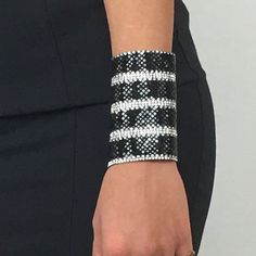 "A classy geometric black & white crystal bracelet that shines and brings a special spark to your looks. Made of colourful crystals it wraps around your wrist adding a sparkling twist to your style. It closes around the hand with an invisible strap, so it beautifully decorates your hand all around. The standard width of the bracelet is 3,54\" and the perimeter is for wrists up to 7,48\" inches. However as it is hand crafted in our studio we could gladly have it custom made to your desired wr Crystal Bangle Cuff Bracelet For Party, Modern Metal Beaded Bangle Bracelets, Trendy Crystal Bracelets With Rhinestones, Trendy Crystal Bracelets For Party, Glamorous Crystal Cuff Bracelet For Party, Silver Beaded Bracelets With Strap For Party, Trendy Party Bracelets With Rhinestones, Trendy Adjustable Black Crystal Bracelet, Trendy Crystal Bracelet For Party