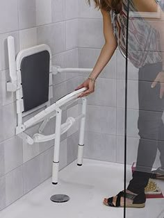 a woman standing in front of a shower with her hand on the side of it