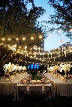 an outdoor dining area with lights strung over the tables and flowers on the tablecloths