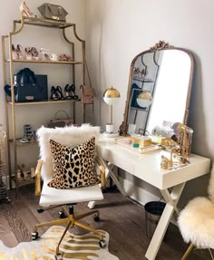 a white desk with a leopard print pillow on it and a gold framed mirror in the corner