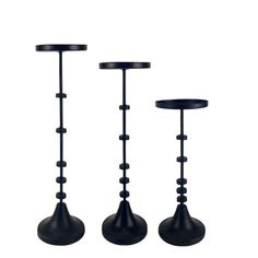 three black candlesticks are standing next to each other on a white background,