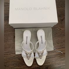 New In Box With Protective Dust Bag Manolo Blahnik Trinamu 50 Satin Embellished Sandals Size 37 / Size 6 Cream / Off White Perfect For Wedding Activities, Baptisms, Or Formal Events. Combining Glamour And Sophistication, Manolo Blahnik's Trinamu Sandals Are Highlighted With Shimmering Crystal-Embellished Vamp Straps. This Italian-Made Pair Is Crafted Of Elegant Satin. Satin Upper Round Open Toe Slip-On Style Leather Sole Made In Italy Size Satin Covered Low-Heel, 2" (50mm) Luxury Stone Embellished Sandals For Formal Occasion, Wedding Leather Sandals With Rhinestones, Designer White Embellished Sandals, Chic Embellished Sandals For Wedding, Designer White Sandals For Cocktail, Elegant Embellished Pointed Toe Sandals, Designer White Sandals For Wedding, Chic Embellished Sandals For Formal Occasions, White Embellished Sandals For Formal Occasions