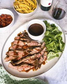 a plate with steak, french fries and salad on it next to some condiments