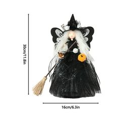 a black and white witch doll with a broom on it's head, standing in front of a white background