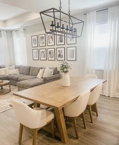 a dining room table with chairs and pictures on the wall above it in front of a couch