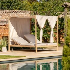 an outdoor bed with curtains over it next to a swimming pool in a garden area