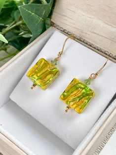 "Abstract swirls of green and gold flow though these artisan created Murano glass beads! Each earring is also adorned with complimentary color Swarovski crystal. The earrings hang 1.5 inches on Vermeil brushed gold ear wires.  The glass beads are 15mm squares that are comfortable and easy to wear. A wonderful gift for any occasion and arrives in a standard gift box. ✨ Authentic Murano Glass: Each pair of earrings showcases the unparalleled beauty of Murano glass, renowned for its vibrant colors Petrified Wood Jewelry, Murano Glass Earrings, Abstract Jewelry, Murano Glass Jewelry, Italian Jewelry, Murano Glass Beads, Complimentary Colors, Wood Jewelry, Venetian Glass