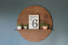 a wooden shelf with potted plants on it and a sign that says party of 6